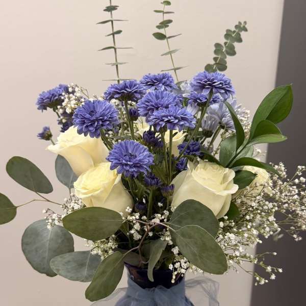 Blue and white bouquet in a dark vase with a tulle bow