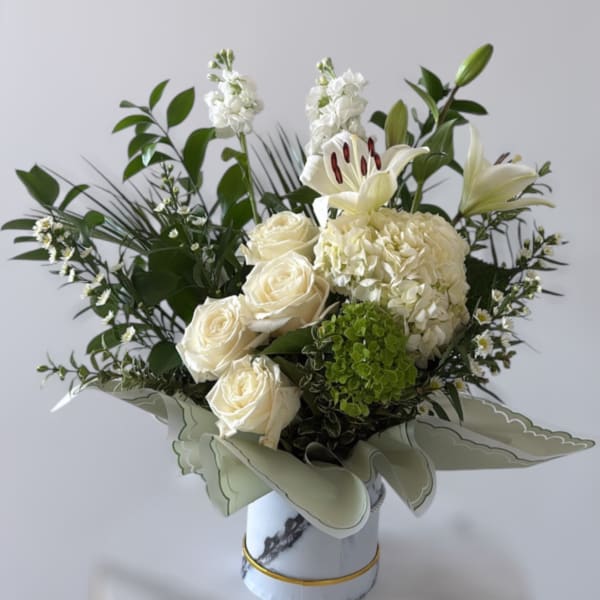 White roses, lilies, and hydrangea in a decorative vase