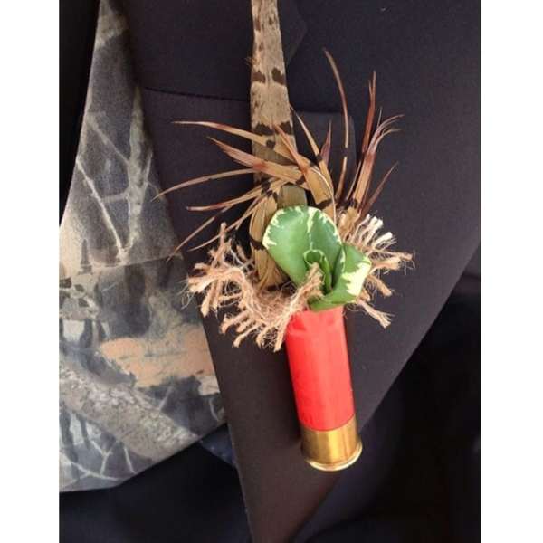 Small boutonniere with green leaves and dried grasses on a red shell casing