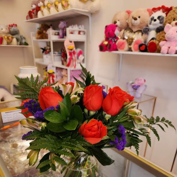 Bouquet of red roses and purple filler flowers in a glass vase
