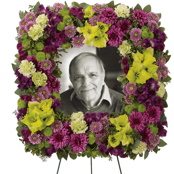 Floral funeral wreath on an easel with a portrait in the center