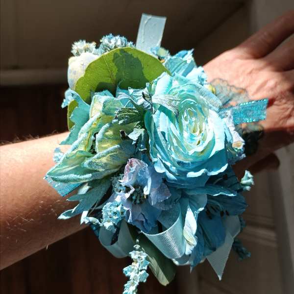 Blue floral wrist corsage with ribbon and greenery