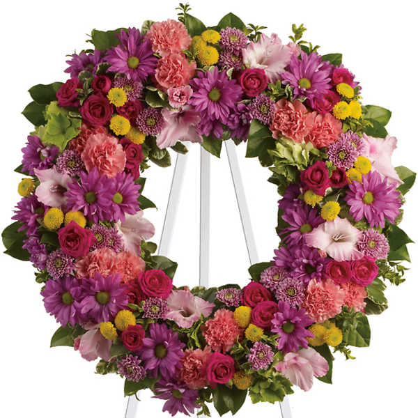 Heart-shaped floral wreath on a white easel with pink, purple, and yellow flowers