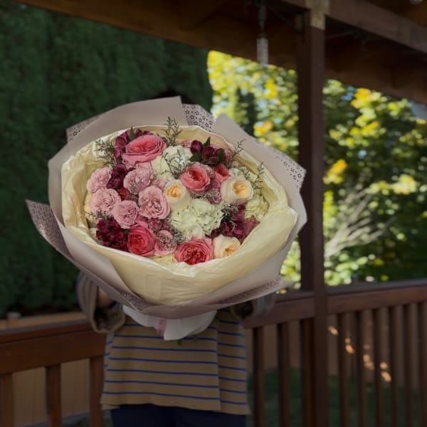 Large bouquet of pink and white roses wrapped in cream paper