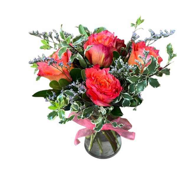 Bouquet of coral roses in a glass vase with a pink ribbon