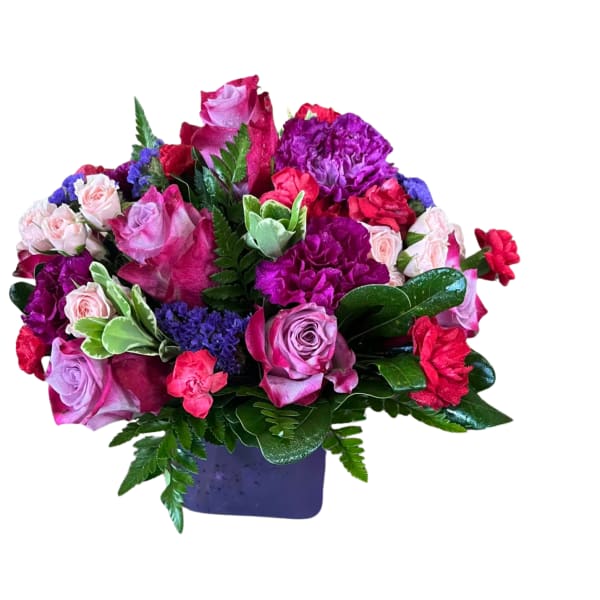 Mixed pink, purple, and red flower arrangement in a purple vase