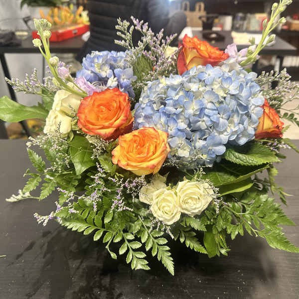 Bouquet of blue hydrangeas and orange roses with white roses