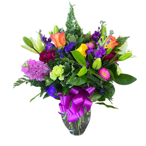 Mixed bouquet of colorful flowers in a glass vase with a purple ribbon