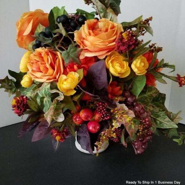 Bouquet of orange and yellow roses with berries in a white container
