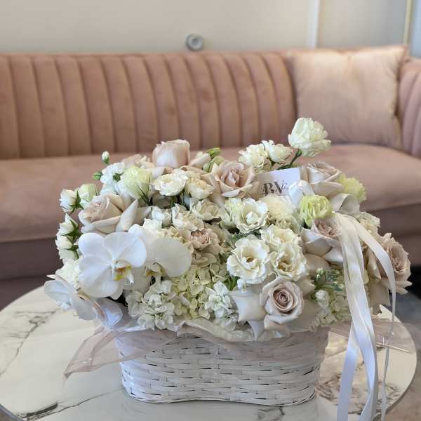 Cream and blush bouquet in a white basket with ribbon