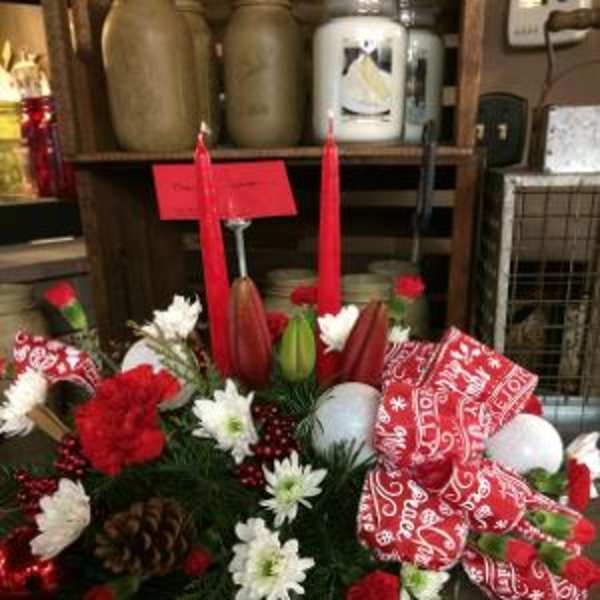 Red and white floral arrangement with candles and a patterned ribbon