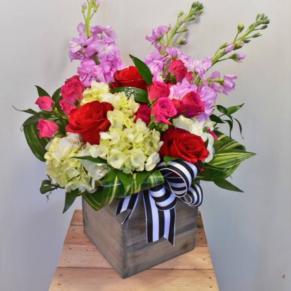 Pink and red roses with pale hydrangeas in a wooden box