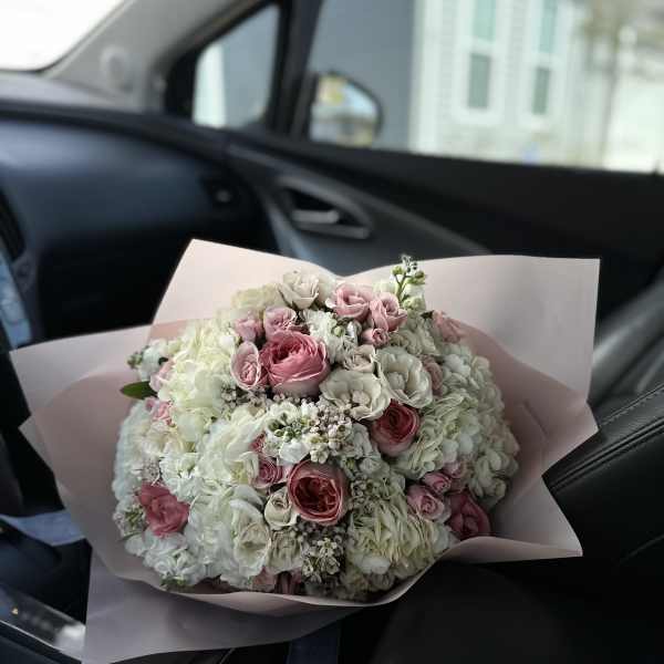 Bouquet of pink and white roses wrapped in pale pink paper