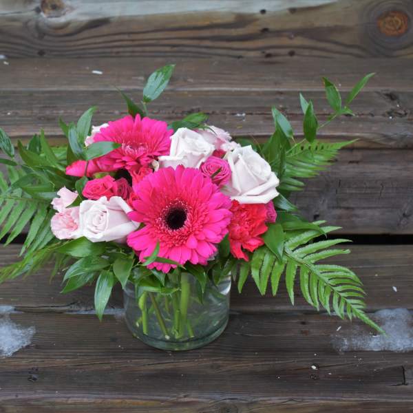 Pink gerbera daisies and roses in a glass vase