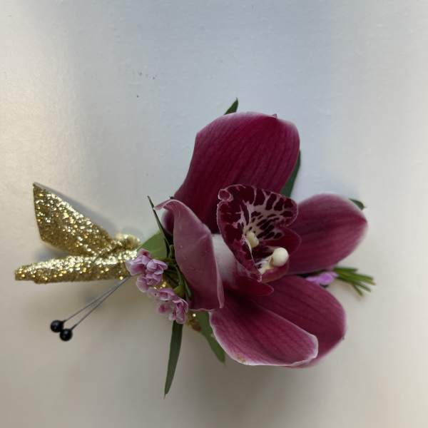 Magenta orchid corsage with small pink blooms and gold glitter accents on a white background