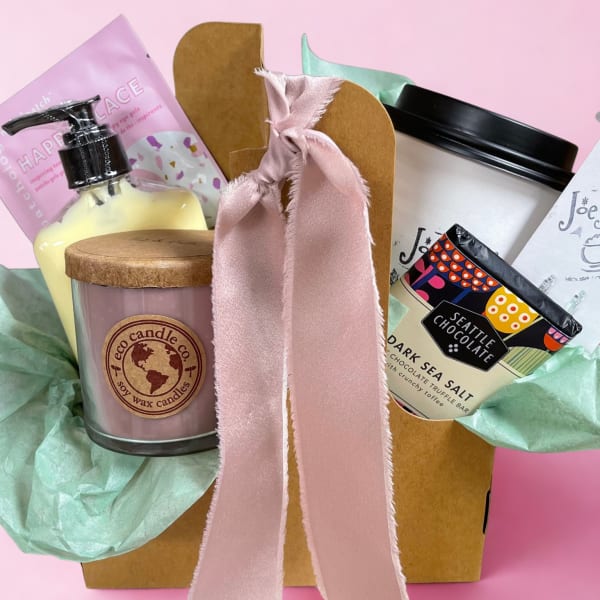 Gift basket with a candle, lotion, and chocolate bar tied with a pink ribbon