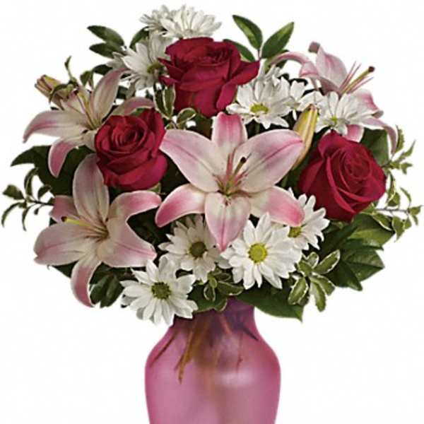 Bouquet of pink lilies, red roses, and white daisies in a pink vase