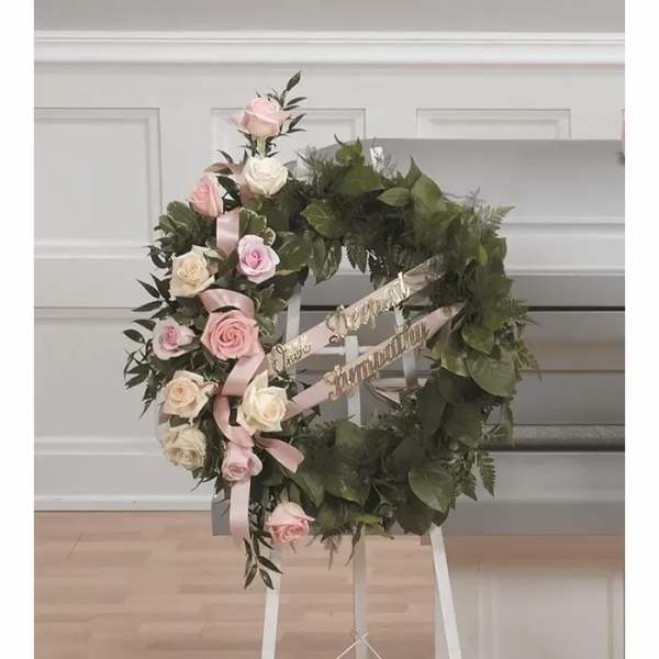 Heart-shaped floral wreath with pink and white roses on an easel