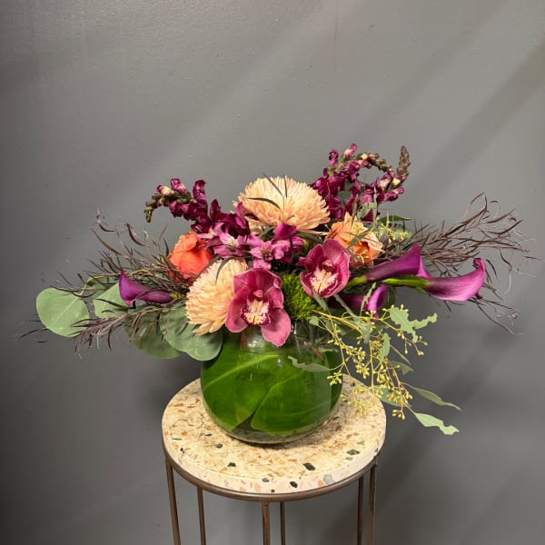 Mixed floral arrangement in a round green glass vase