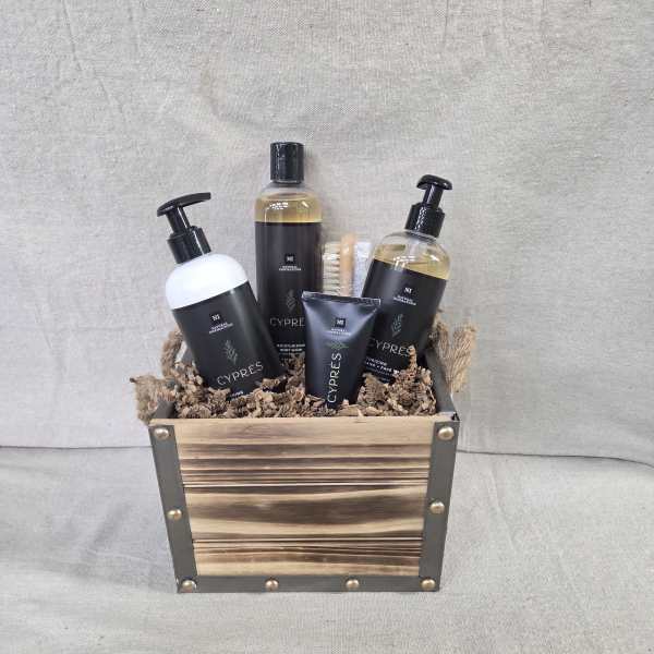 Wooden crate filled with black-labeled bath products and a small brush on shredded paper filler