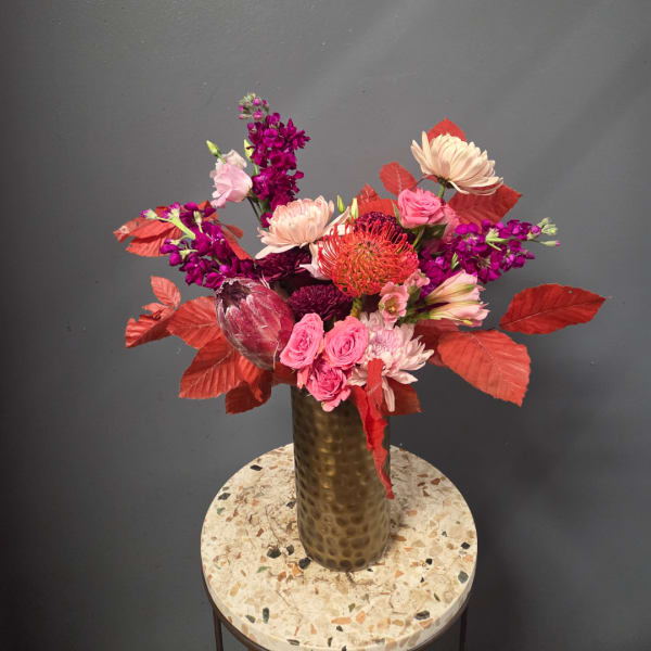 Pink and purple mixed bouquet in a tall gold vase