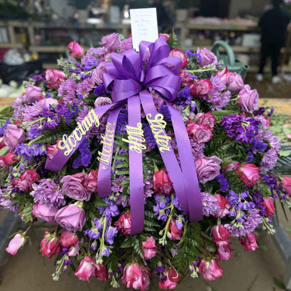 Large purple and pink floral spray with ribbon and name tags