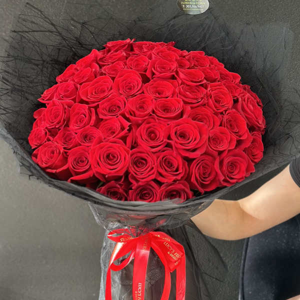 Large bouquet of red roses wrapped in black mesh with a red ribbon