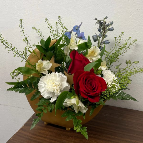 Red roses and white carnations in a gold vase with blue accents