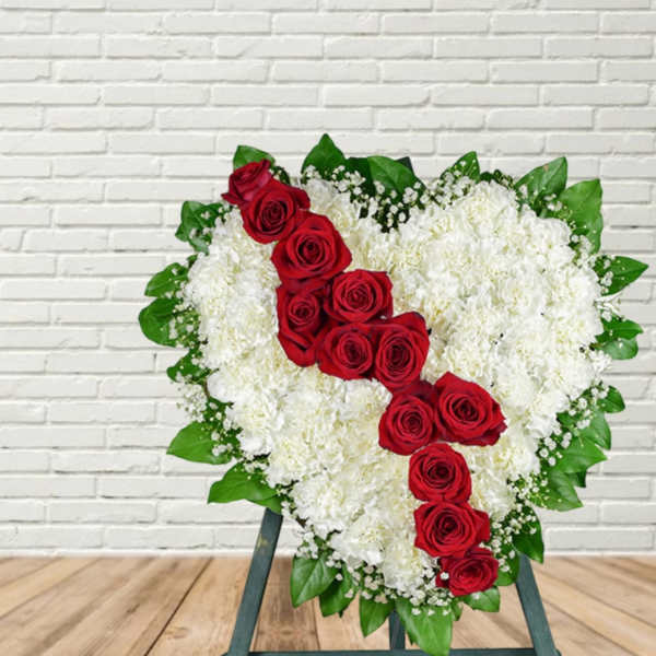 Heart-shaped floral spray with red roses and white flowers on a stand