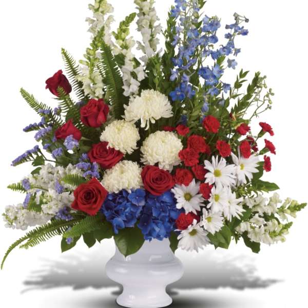 Mixed red, white, and blue floral arrangement in a white vase