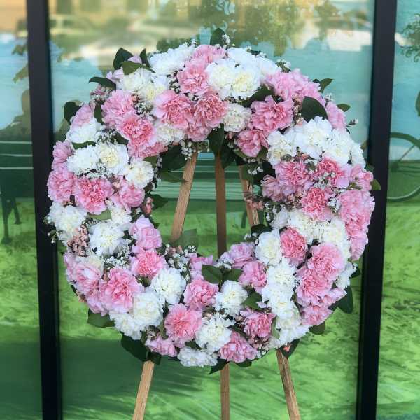 Pink and white carnation wreath on a wooden stand