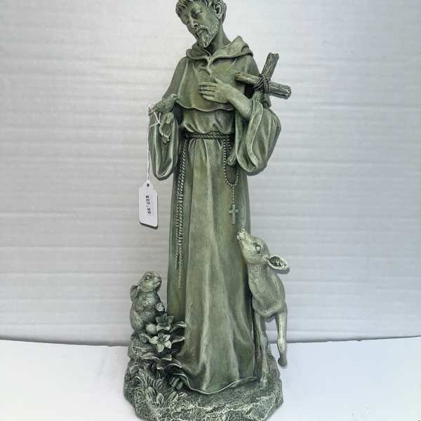 Green religious statue of a saint with a cross and two animals at the base