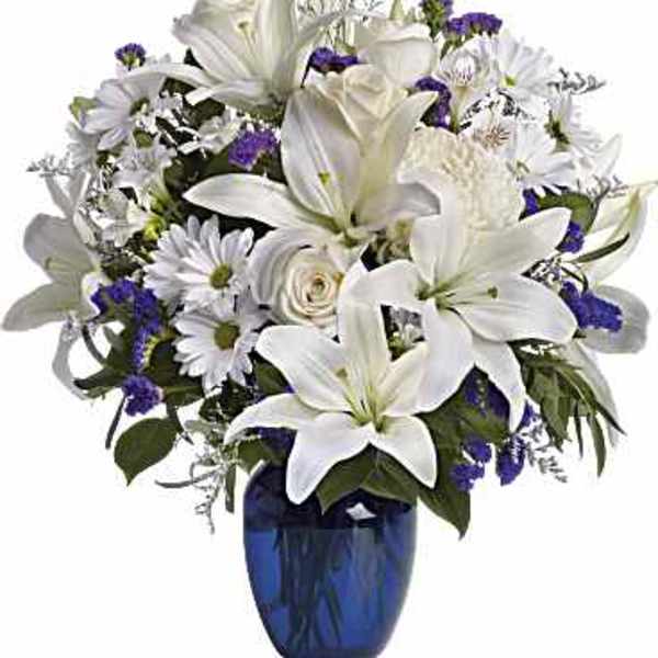 White lilies and daisies in a blue glass vase