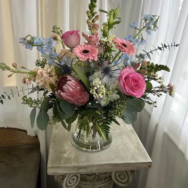 Mixed bouquet in a clear glass vase with pink and blue flowers