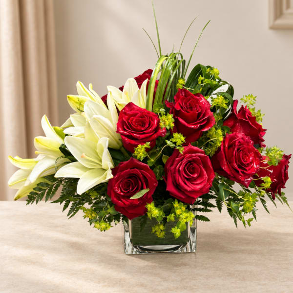 Red roses and white lilies arranged in a clear square vase