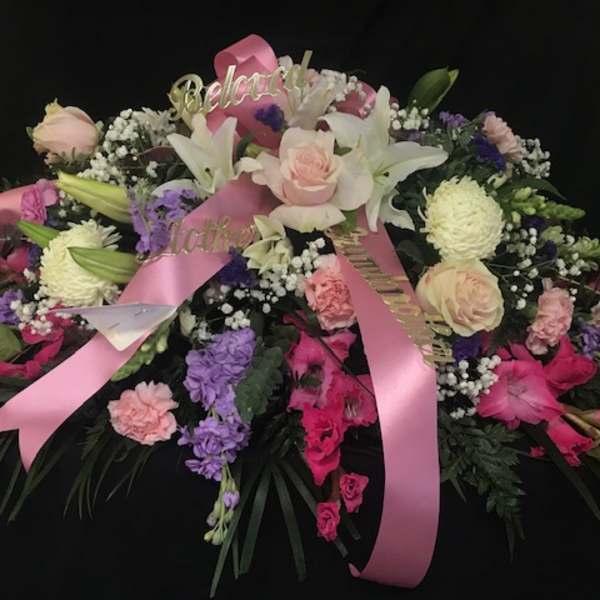 Large pink and white floral spray with ribbons on a black background
