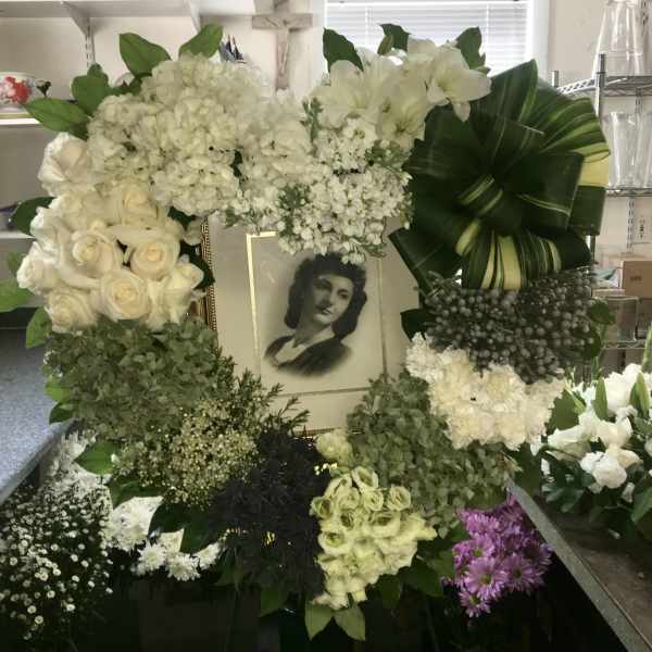 Large white funeral wreath with a framed portrait in the center