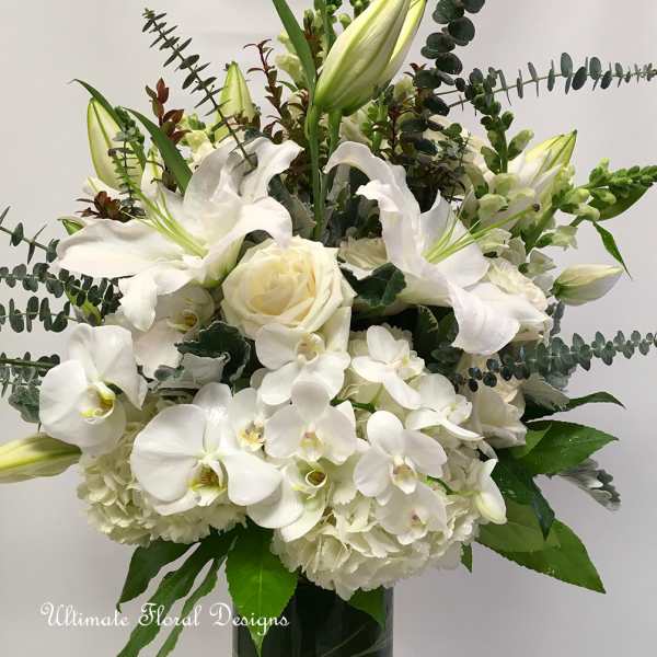 White lilies, roses, and orchids arranged in a vase