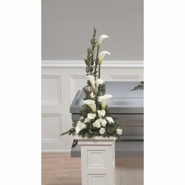 Tall white floral spray beside a gray casket