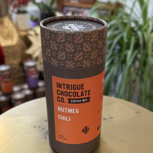 A cylindrical tin of cocoa mix labeled Nutmeg Chili.
