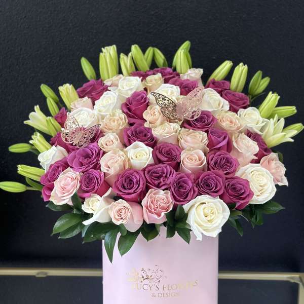 Pink, white, and peach roses in a round pink box with lily buds