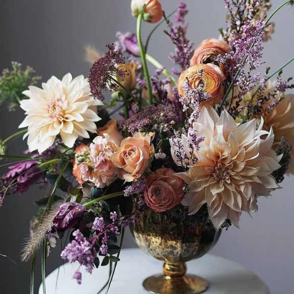 Peach and cream floral arrangement in a gold vase