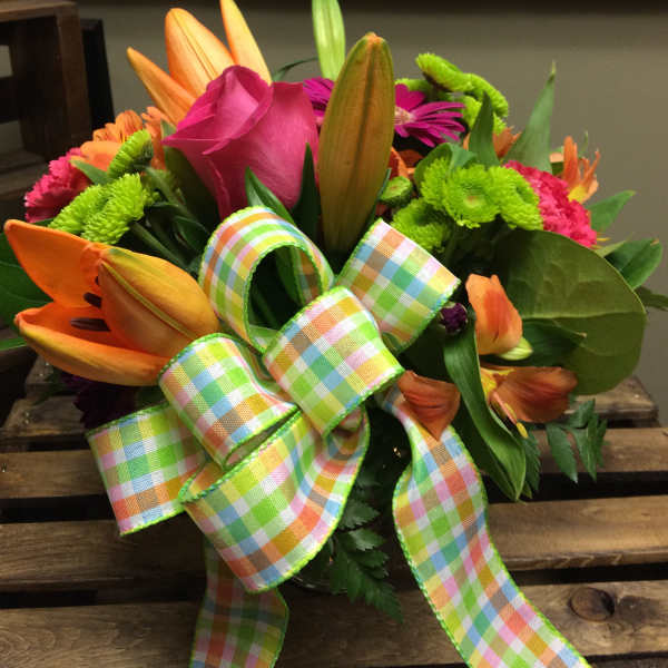 Bright mixed bouquet with lilies, roses, and a plaid ribbon bow