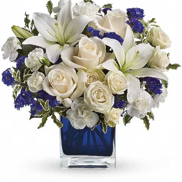 White lilies and roses arranged in a blue glass vase