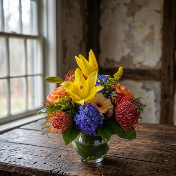 Mixed bouquet in a glass vase with yellow lilies and colorful blooms