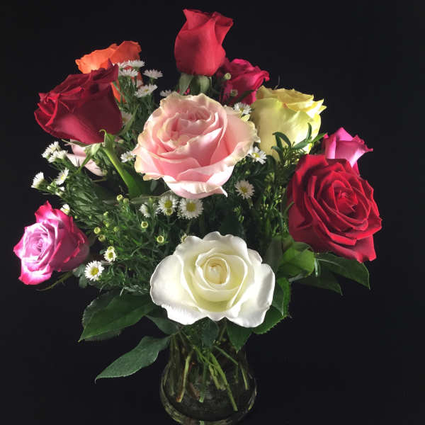Mixed roses in a clear glass vase with small white filler flowers