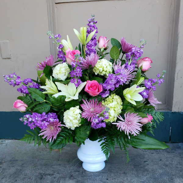 Pink roses, white lilies, and purple flowers in a white vase