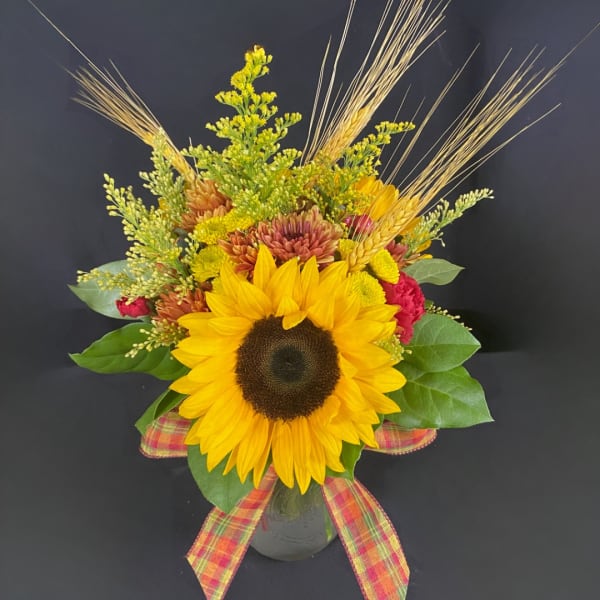 Sunflower arrangement in a glass vase with plaid ribbon