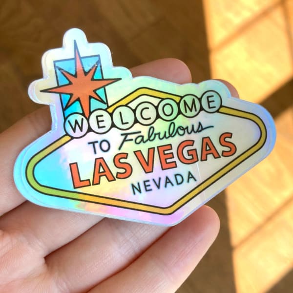 Hand holding a holographic Las Vegas sticker with text