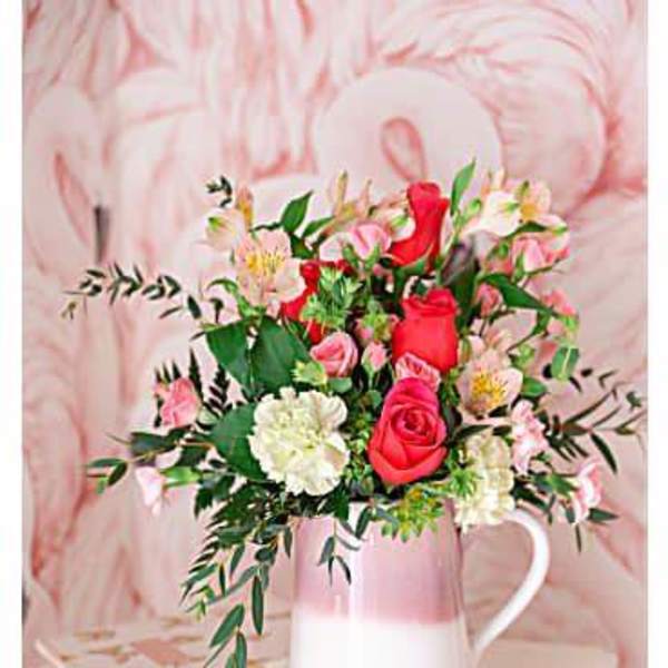Pink and red rose bouquet in a white pitcher vase